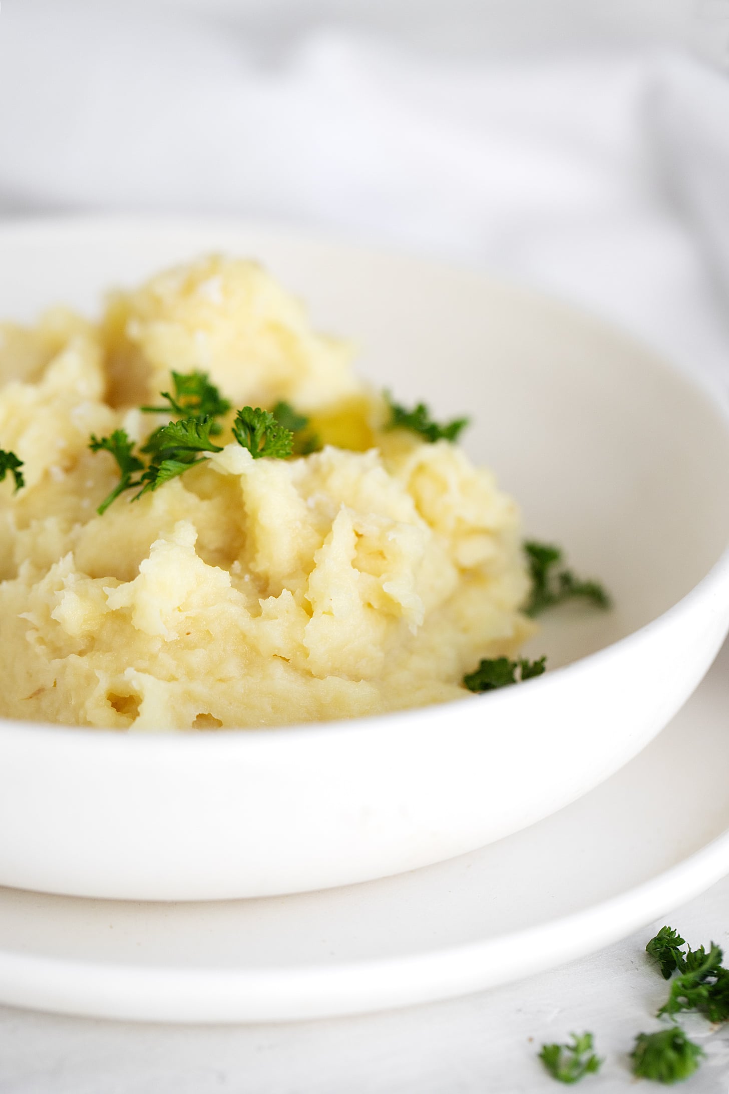 Parsnip puree in white bowl with parsley garnish.