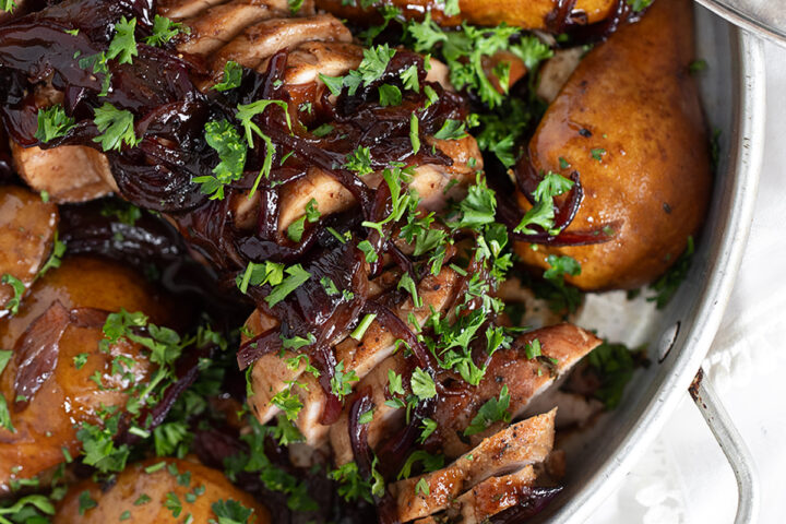 Pork tenderloin with pears and balsamic onions in serving dish.
