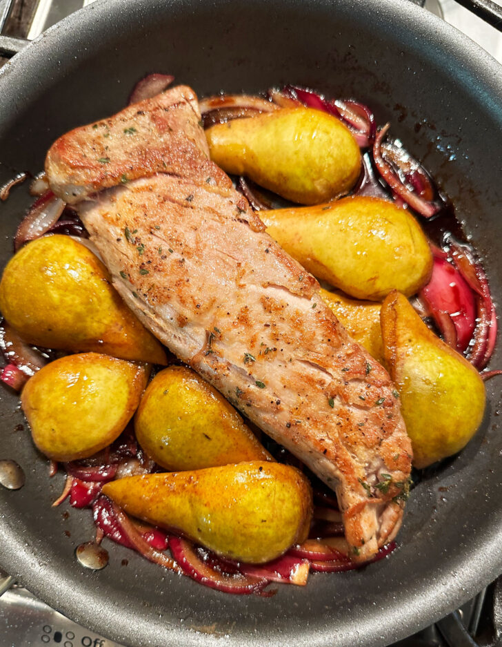 Pears, pork and onions assembled in skillet before placing in the oven.