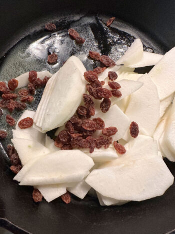 adding prepared apples and raisins to skillet