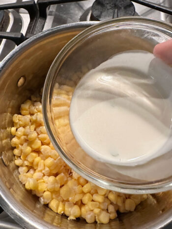 adding cream to corn in saucepan