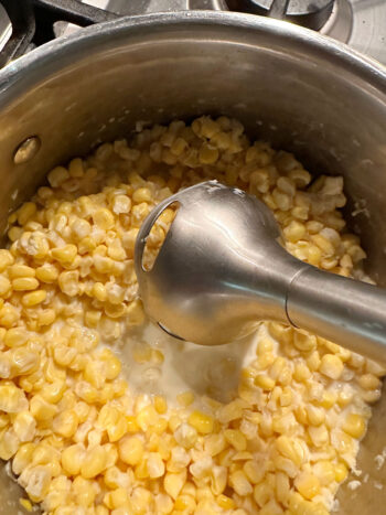 using an immersion blender to break down the corn