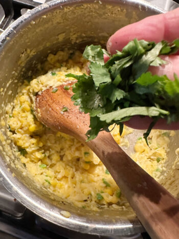 adding cilantro to corn in saucepan