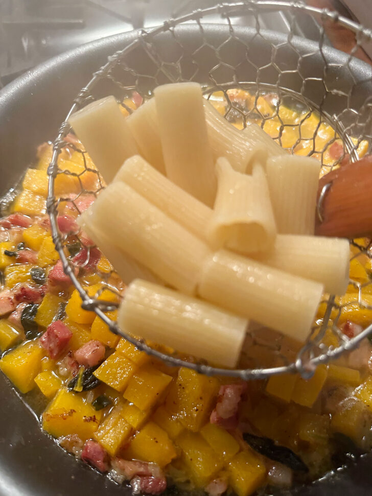 adding cooked pasta to sauce