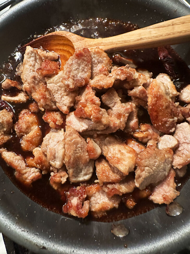 returning pork to the skillet with the sauce