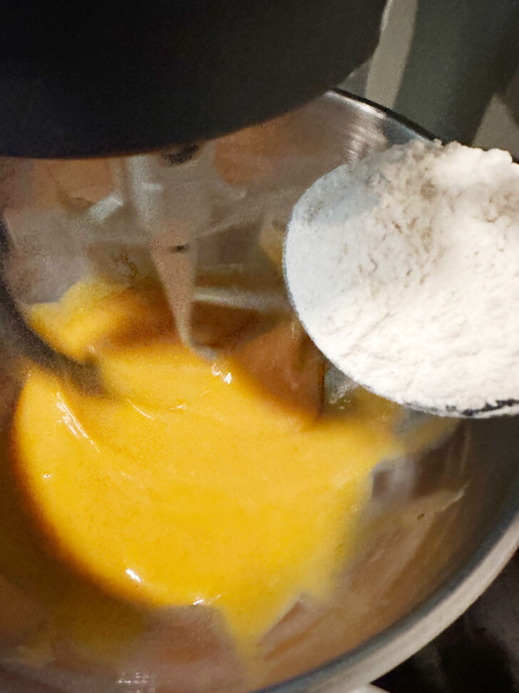 adding dry ingredients to wet ingredients in mixer bowl