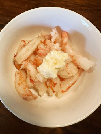 adding ginger garlic paste to shrimp in bowl