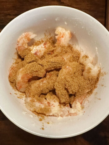 adding spice mix to bowl with shrimp