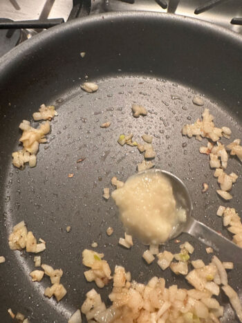 adding ginger garlic paste to skillet with cooked onions
