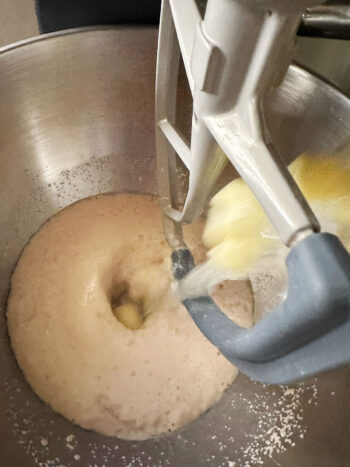 adding butter water mixture to mixer with yeast mixture