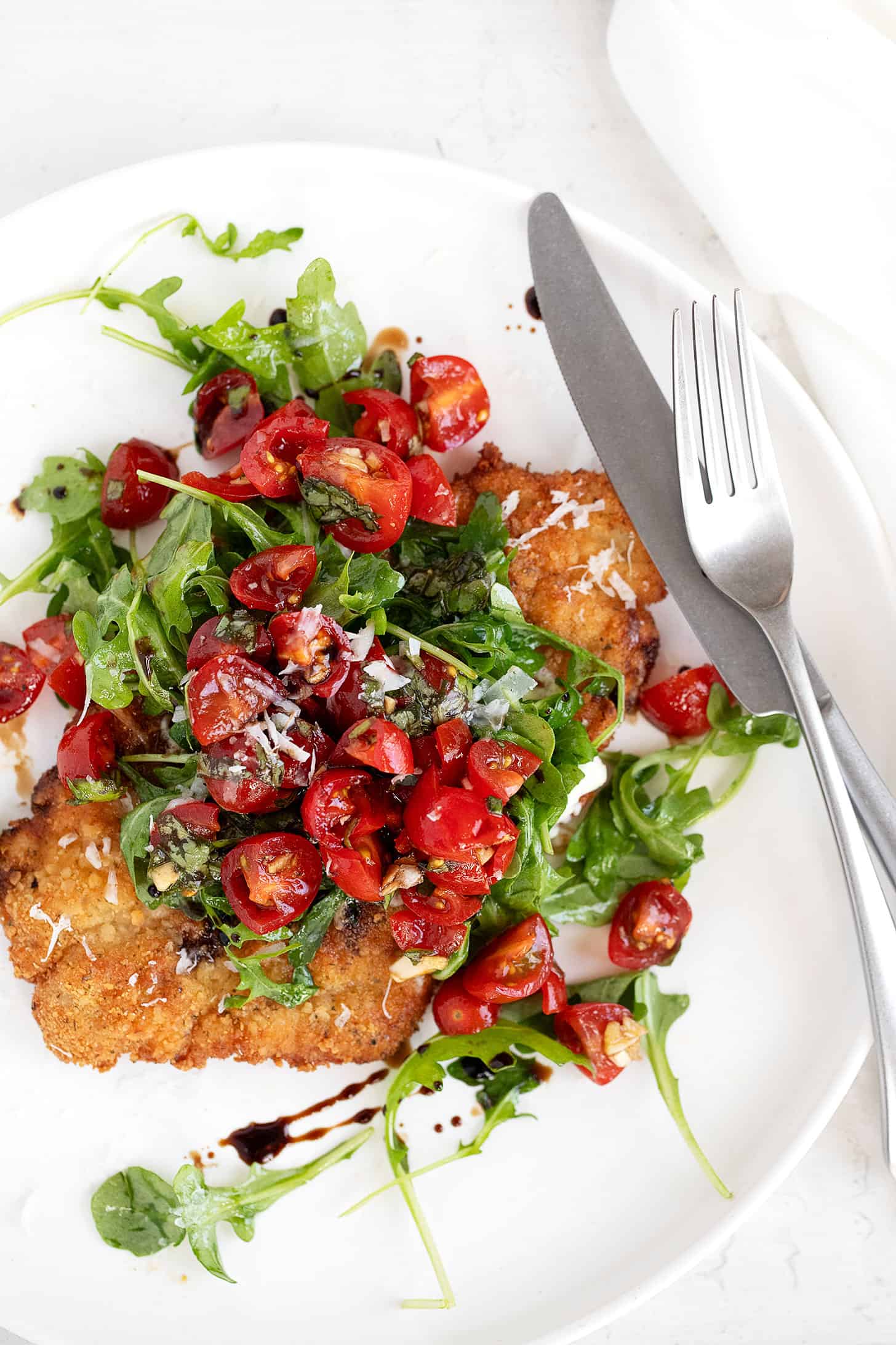 pork Milanese on plate with arugula and bruschetta topping