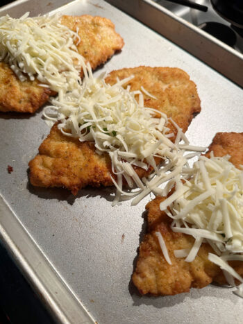 sprinkling mozzarella over fried pork cutlets before putting in the oen