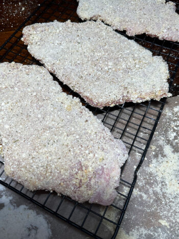 breaded pork cutlets on wire rack before chilling