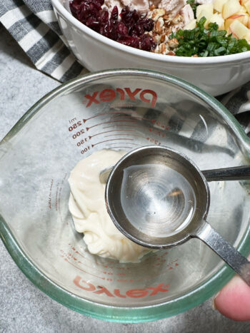 adding vinegar to mayonnaise in a measuring cup