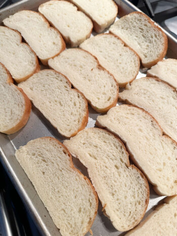 bread slices on baking tray before toasting