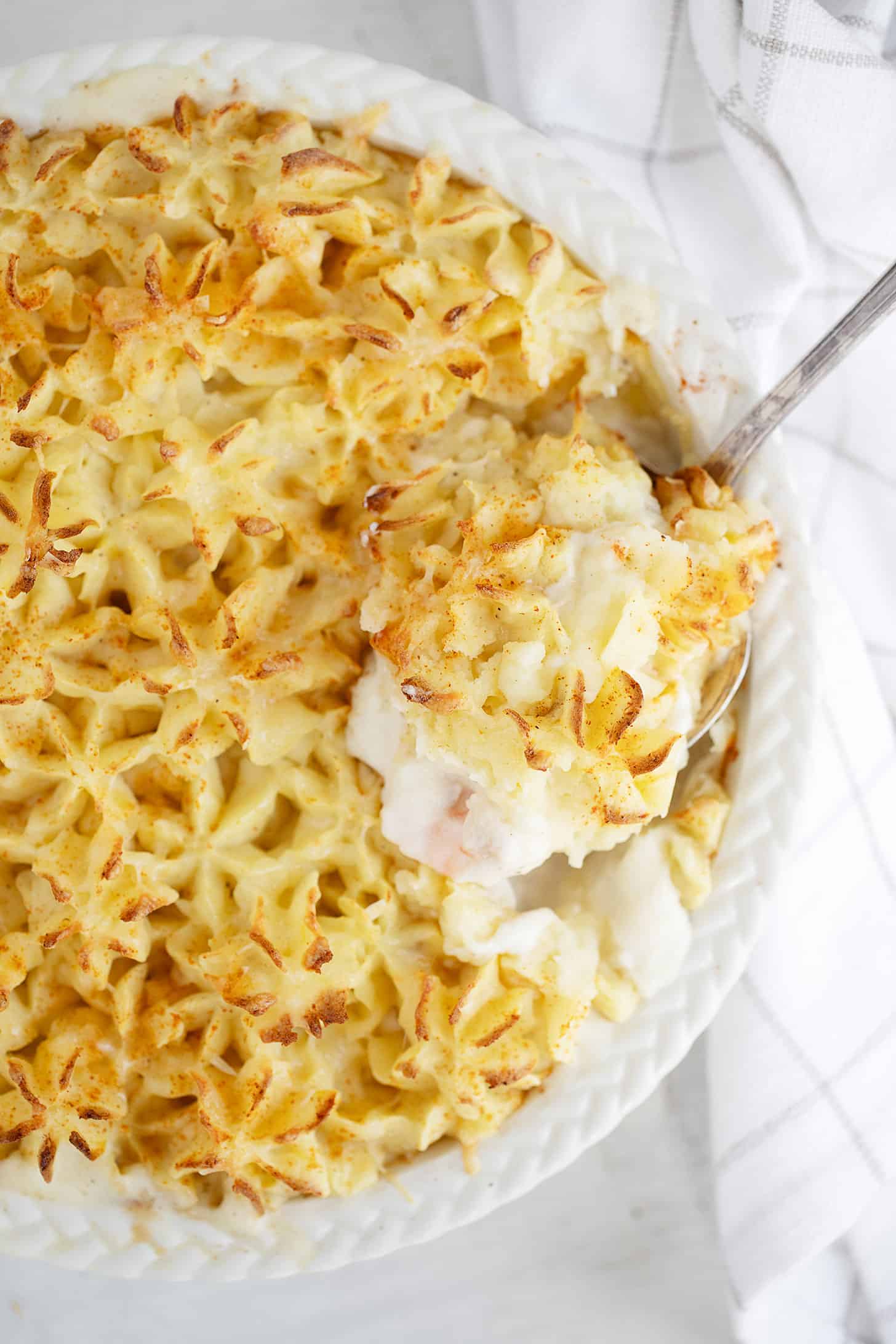 Fish pie in baking dish with spoon