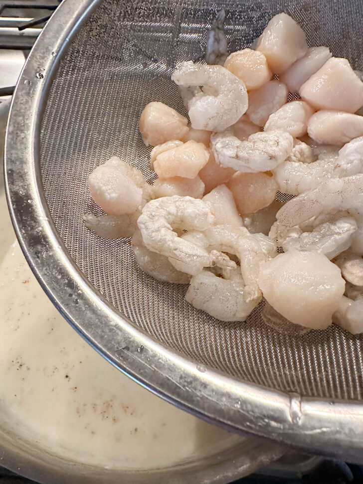 adding shrimps and scallops to white sauce