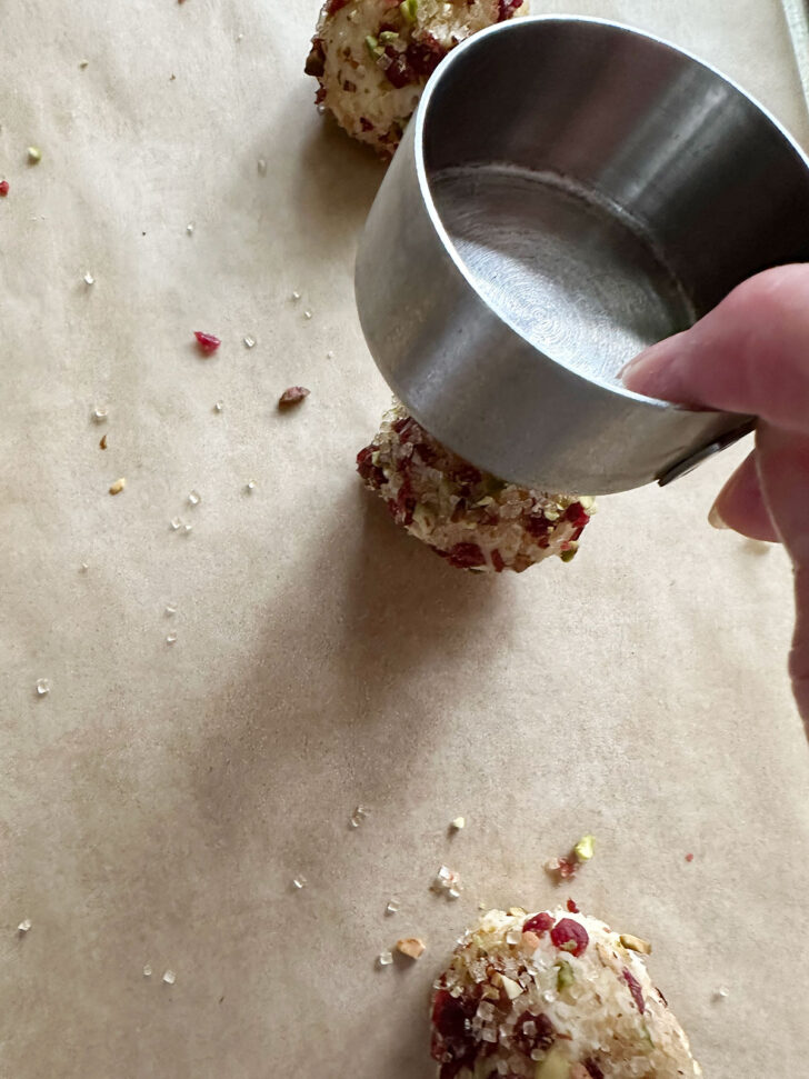 flattening dough balls with the bottom of a measuring cup