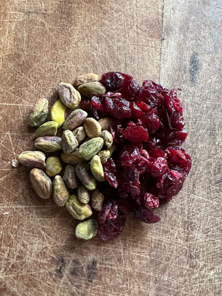 dried cranberries and pistachios on cutting board