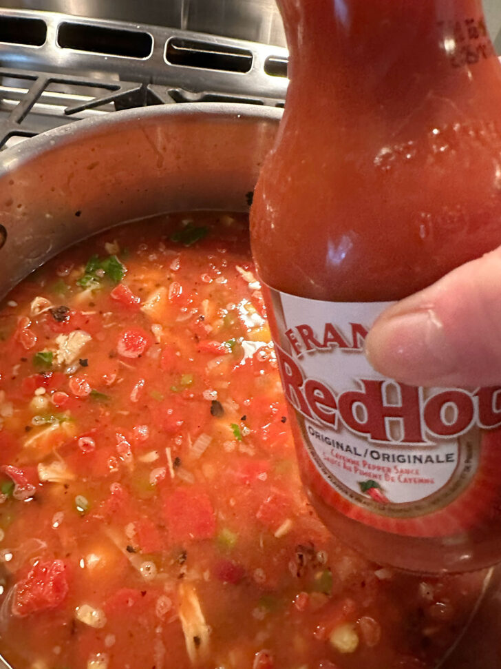 adding some hot sauce to the soup