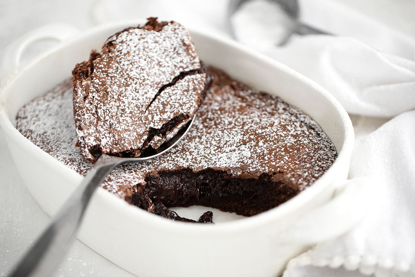 The chocolate brownie cake in baking dish with spoon.