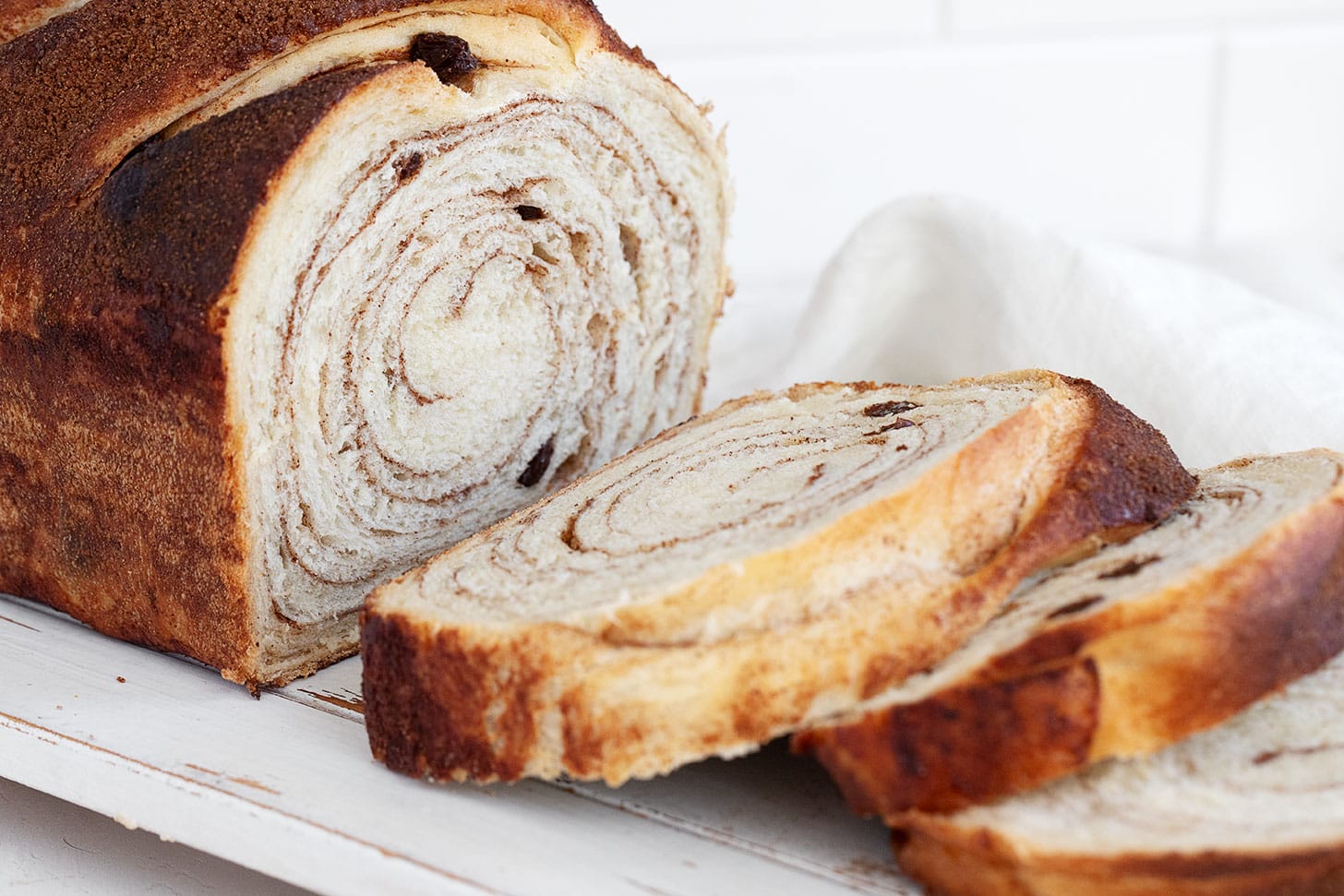 Cinnamon swirl bread with raisins sliced on a cutting board.