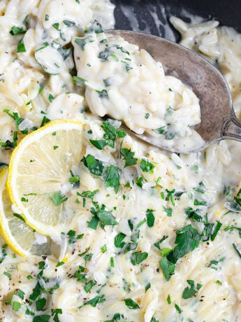 Creamy lemon parmesan orzo in skillet with spoon.