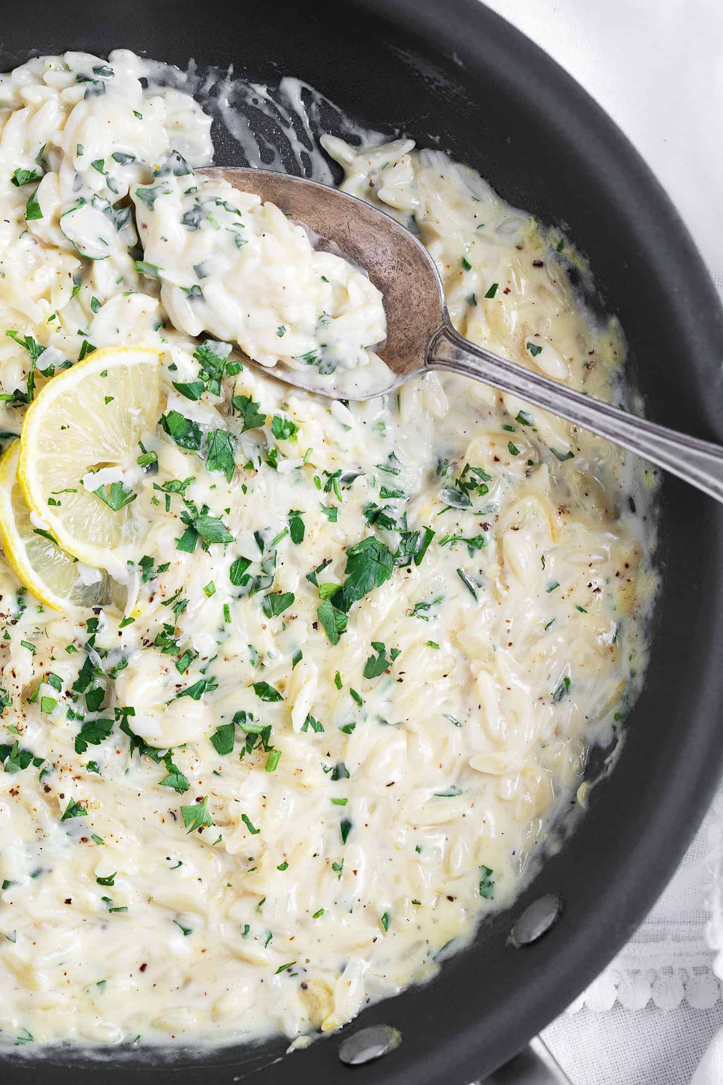Creamy lemon orzo in skillet with spoon.