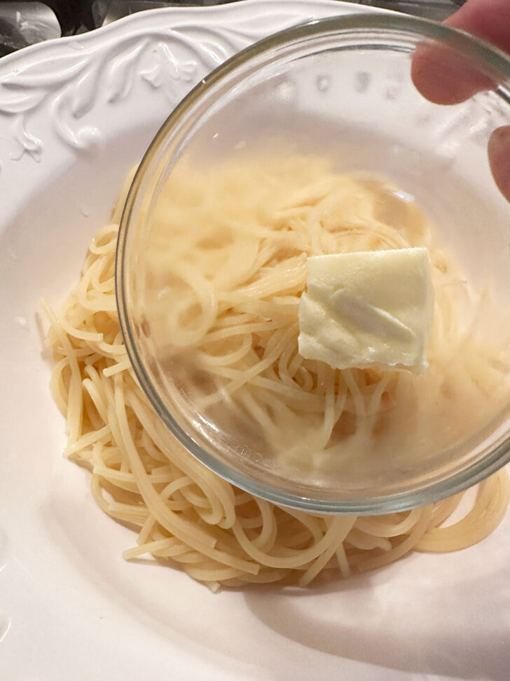 Adding butter to cooked pasta.