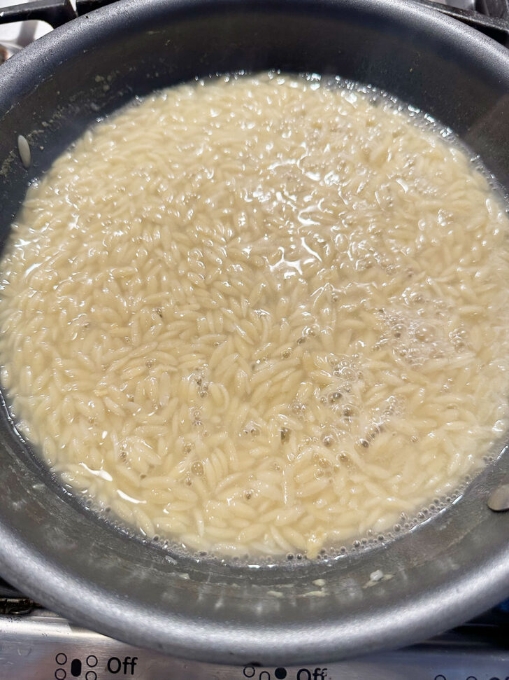 Orzo cooking in chicken broth.