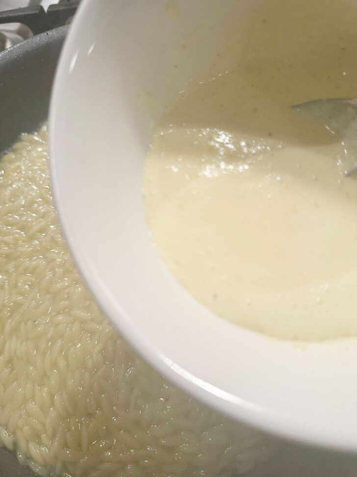 Adding the lemon sauce to the cooked orzo.