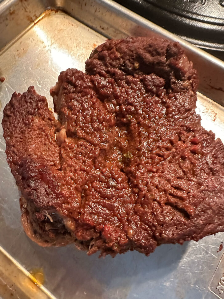 Removing beef from the baking dish.