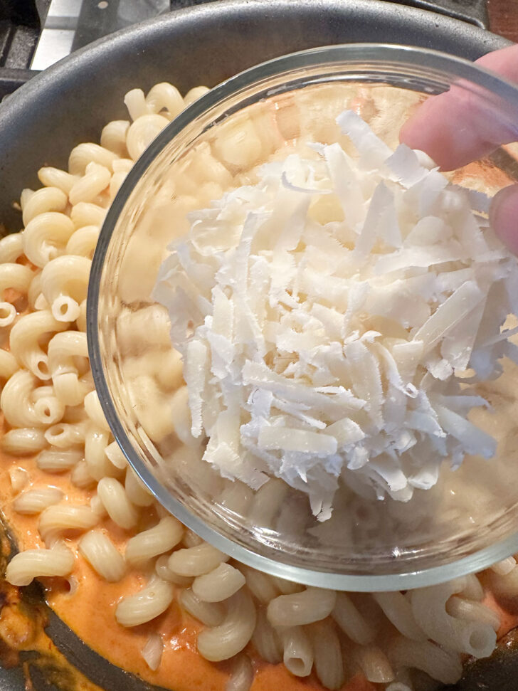 Adding Parmesan cheese to the skillet.