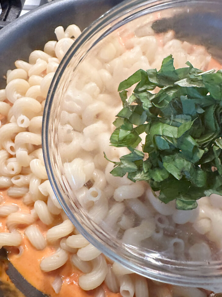 Adding basil to the skillet.