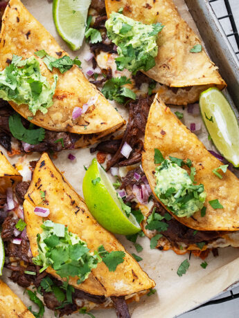 Mexican shredded beef tacos on baking sheet.