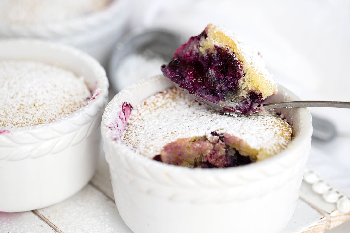 Blueberry pudding cake in ramekins with spoon.