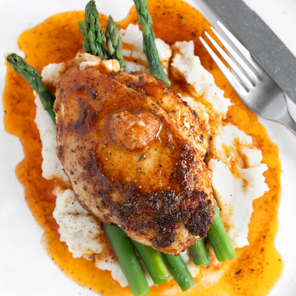 Cajun chicken on plate with asparagus and mashed potatoes.