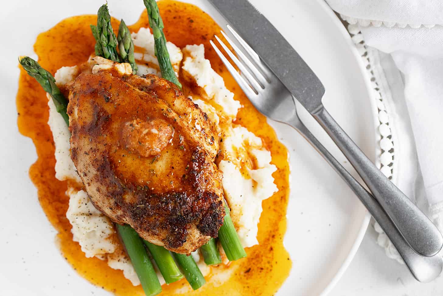 Cajun chicken on plate with mashed potatoes and asparagus.