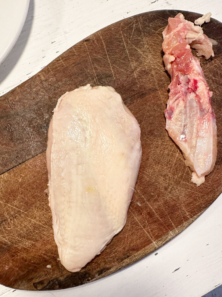 Removing the bone from the chicken breast.