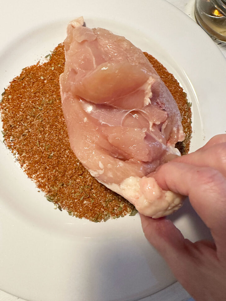Dipping the chicken breast in spice mix.