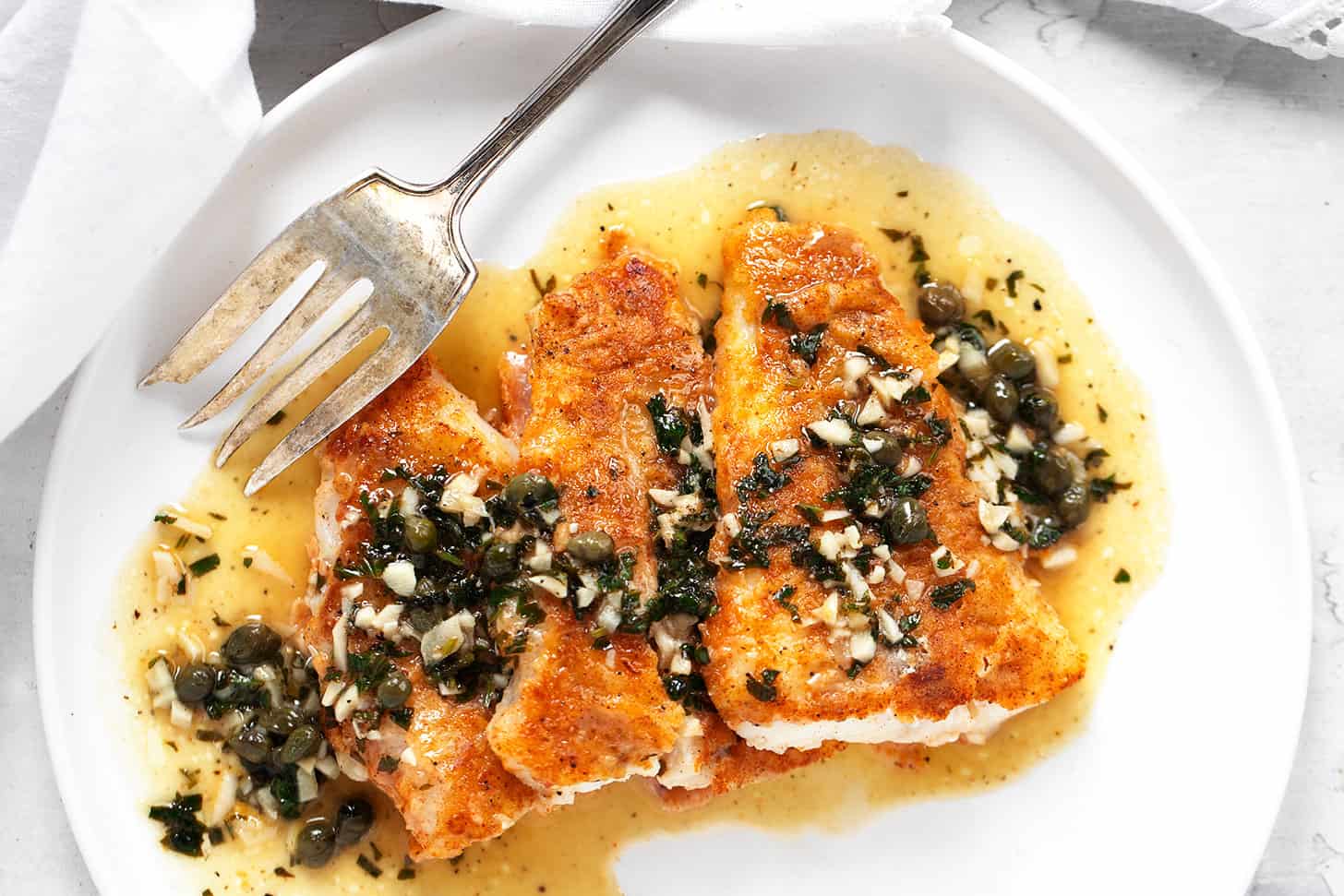 Cod piccata on plate with fork.