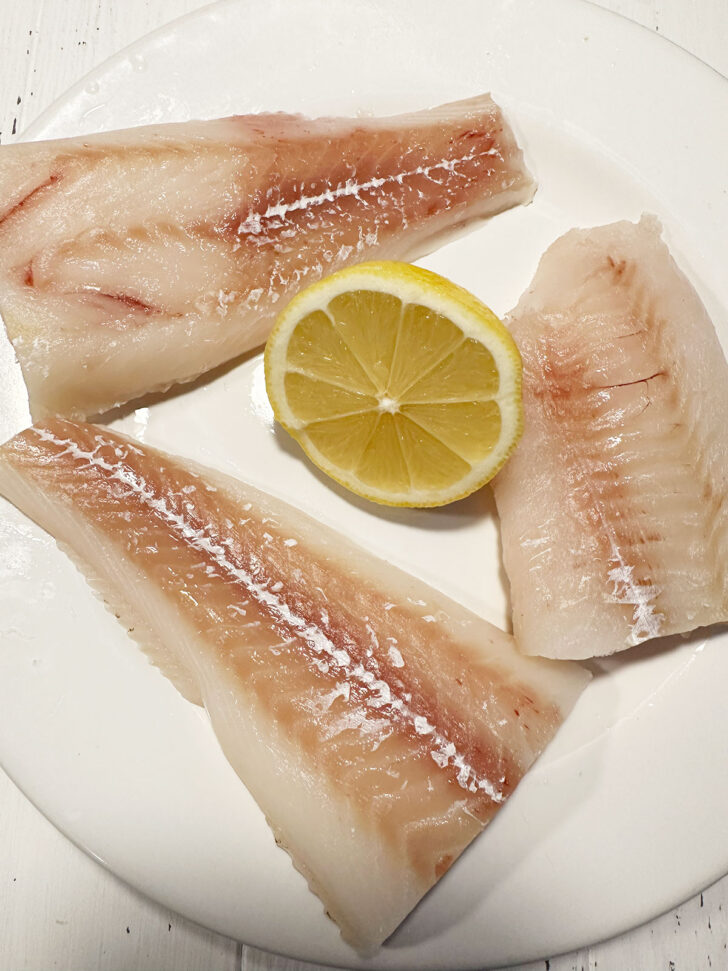Cod fillets on plate with half a lemon.