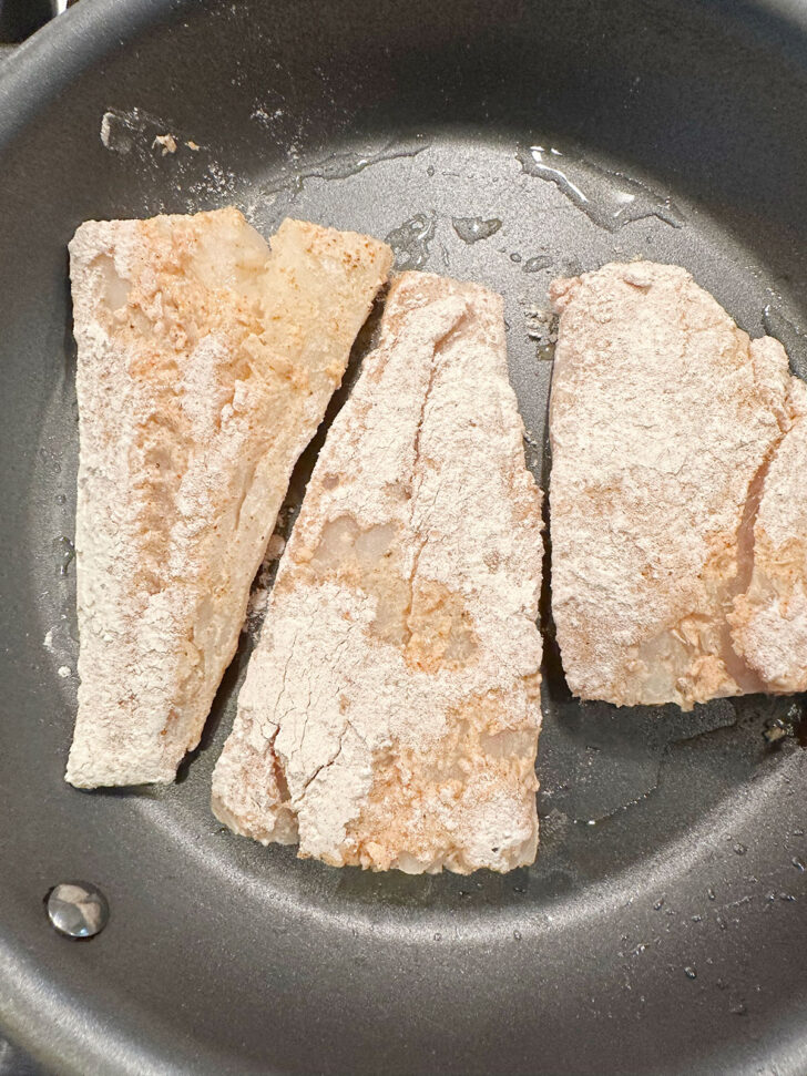 Floured cod fillets in hot skillet.