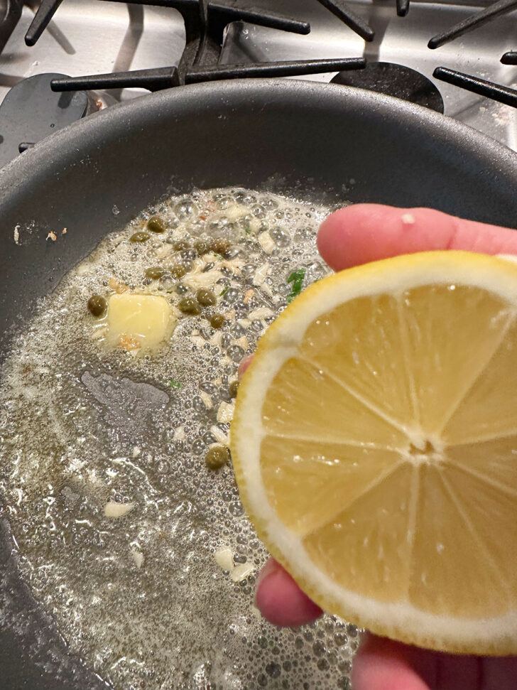 Adding lemon to the sauce in the skillet.