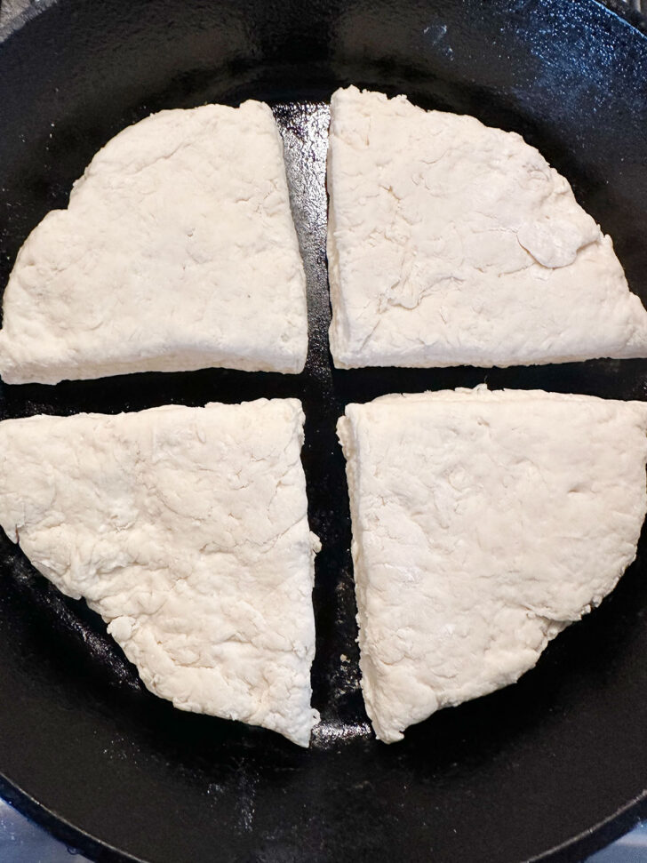 Dough quarters placed in a warm cast iron skillet.