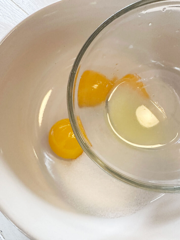 Adding lemon juice to egg yolks and sugar in a small bowl.