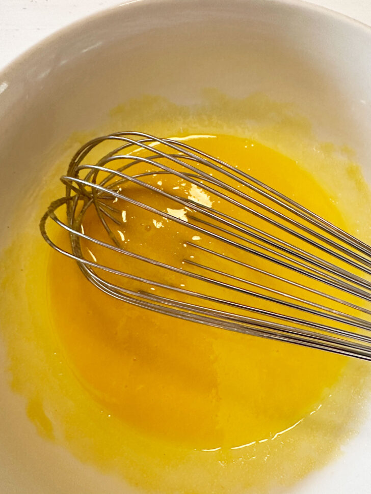 Eggs and sugar whisked together in bowl.
