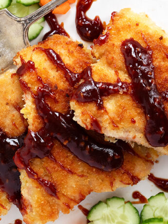 Salmon katsu on plate with cucumbers and carrots.