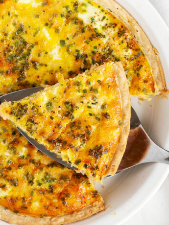 Salmon quiche in pie dish with a sliced on server.