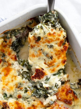 Baked Tuscan chicken in baking dish with spoon.